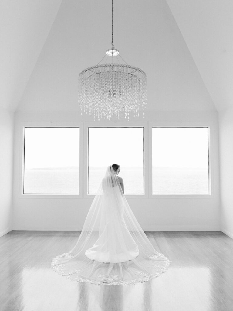 bride with spread out veil in getting ready suite at belle mer in an all white room with large window